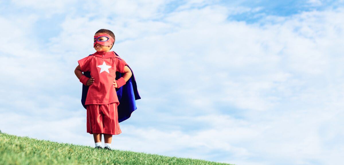 Young boy standing on hillside dressed as a super hero